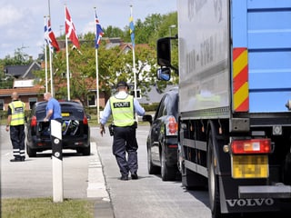 Dänische Beamte in Signalwesten kontrollieren Fahrzeuge am deutsch-dänischen Grenzübergang Pattburg.