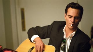 Ein Mann mit einer Zigarette im Mund spielt Gitarre.