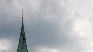 Kirchturmspitze vor bewölktem Himmel 