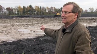 Peter Thomet zeigt auf überschwemmten Acker.