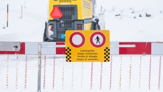 Lawinengefahr-Schild auf eingeschneiter Strasse Lawinengefahr-Schild auf eingeschneiter Strasse