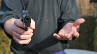 Mann droht mit einer Waffe.