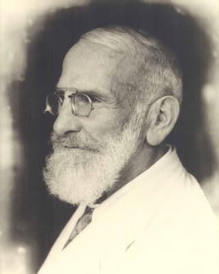 Schwarz-weiss Foto von Maximilian Bircher-Benner mit Bart und Brille im weissen Anzug. Schwarz-weiss Foto von Maximilian Bircher-Benner mit Bart und Brille im weissen Anzug.