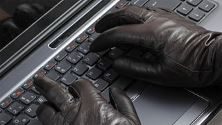 Hand mit Handschuhen auf einer Computer-Tastatur.