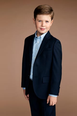 Kind mit braunen Haaren im blauen Anzug