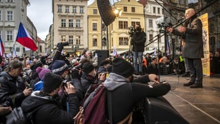 Demonstranten vor einer Bühne, auf der Vaclav Klaus eine Rede hält.