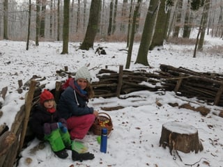Waldsofa mit Betreuerin und Kindern.
