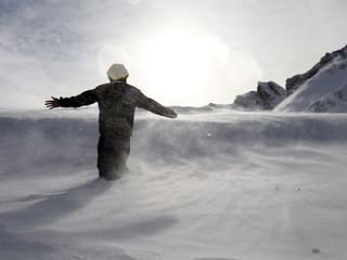 Eine Person steht im Schnee bei stürmischem Wetter