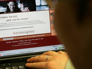 Eine Person sucht am Computer auf einer Vermittlungsplattform nach einem passenden Partner. Eine Person sucht am Computer auf einer Vermittlungsplattform nach einem passenden Partner.