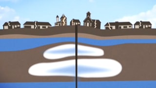 Schematische Darstellung: Um ein Bohrloch herum hebt sich der Boden, die Häuser haben Risse.