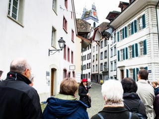 Eine Gruppe von Menschen in der Altstadt von Aarau. Hinten sind einige Gebäude.