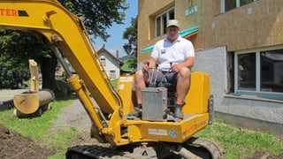Urs Abderhalden sitzt auf einem Gartenbagger vor seinem Haus, das er derzeit umbaut.