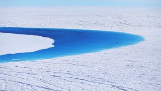 Ein blauer See auf einer schier unendlichen Gletscherfläche.