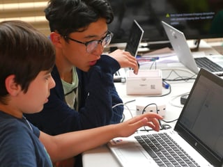 Zwei Jungen schauen in einen Laptop.