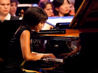 Die chinesische Pianistin Yuja Wang spielt auf einem Steinway, hinter ihr Musiker des Orchesters.
