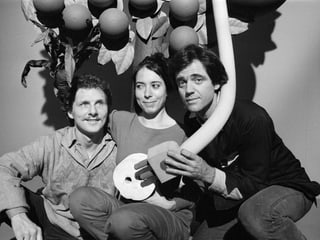 S/W-Bild: Zwei Männer und eine Frau sitzen vor einer Art gebasteltem Baum. Es sind die drei Mitglieder des Trios Mummenschanz mit einem selbstgebastelten Requisit.