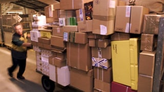Ein Mitarbeiter der Post schiebt einen Wagen mit vielen Paketen. Ein Mitarbeiter der Post schiebt einen Wagen mit vielen Paketen.