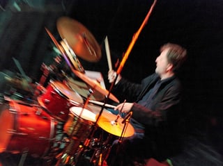 Ein Mann hinter einem Schlagzeug in buntem Licht.