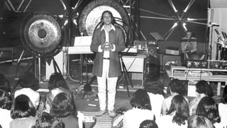 Stockhausen vor grossen Gongs auf einer Bühne vor jungem Publikum Stockhausen vor grossen Gongs auf einer Bühne vor jungem Publikum