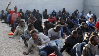 Migranten, die beim Ablegen ihres Schiffes aufgegriffen wurden, sitzen auf einer Polizeistation in Tripoli. 