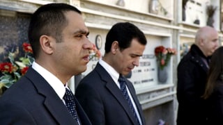 Jovan und José stehen vor einer Grabplatte mit Blumen. Jovan und José stehen vor einer Grabplatte mit Blumen.