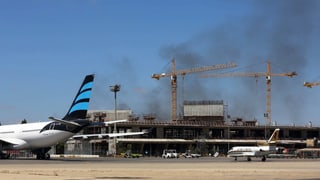 Rauch und kaputtes Gebäude, ein halbes Flugzeug davor.