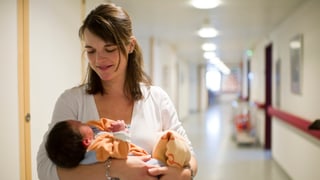 Eine Mutter trägt ihr Neugeborenes durch den Spital 