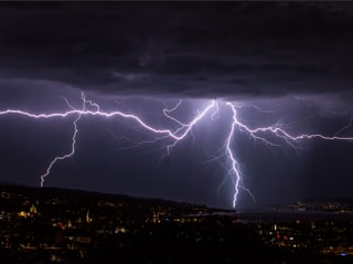 Dunkle Nacht, der Himmel ist dunkelviolett erhellt von vielen Blitzen. 