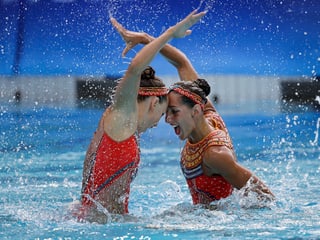 Schwimmerinnen drücken die Stirn aneinander.