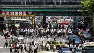 Leute überqueren die Strasse in Japanischer Stadt