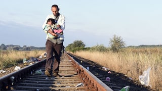 Syrischer Flüchtling mit Kind an der ungarischen Grenze zu Serbien.