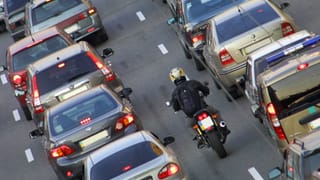 Autokolonnen und ein Motorradfahrer auf einer Autobahn.