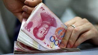 Hände, die chinesische Banknoten zählen.
