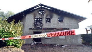 Ein ausgebranntes Haus, das mit einem Polizeiband abgesperrt ist 