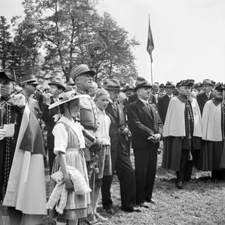 eine schwarz-weiss Fotografie eines Generals, umringt von Menschen in Tracht eine schwarz-weiss Fotografie eines Generals, umringt von Menschen in Tracht
