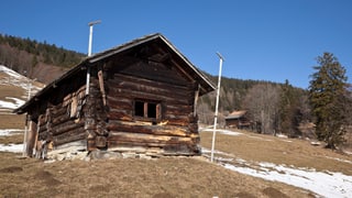 Holzhütte am Hang im Winter, Schneemangel Holzhütte am Hang im Winter, Schneemangel