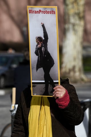 Frau hält Plakat mit der Aufschrift "IranProtests" hoch. 