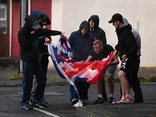 Schwarz gekleidete Jugendliche verbrennen auf der Strasse eine Union Jack-Flagge. Schwarz gekleidete Jugendliche verbrennen auf der Strasse eine Union Jack-Flagge.