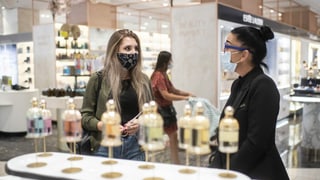 Eine Frau mit Atemschutzmaske testet Düfte, aufgenommen im Warenhaus Jelmoli in Zürich.