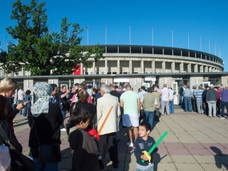 Menschen stehen in einer Reihe vor dem Olympiastadion