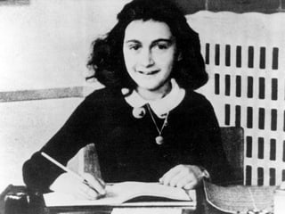 Anne Frank sitzt an ihrem Schreibtisch.