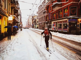 Eine Person auf Skis auf der verschneiten Langstrasse in Zürich.