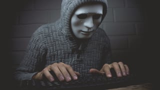 Maskierte Person an einer Tastatur. Maskierte Person an einer Tastatur.