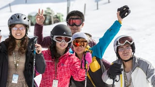 Chinesische Touristen posieren in Skiausrüstung