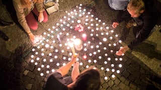 Menschen zünden herzförmigen Kerzen an einer Mahnwache in Zürich 