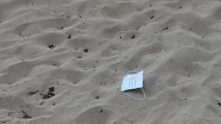 Eine Gesichtsmaske liegt im Sand am Strand von Playa de Palma auf Mallorca.
