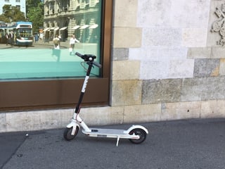 Ein Trottinett vor einem Schaufenster.