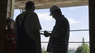Kontrolleur befragt einen Bauarbeiter auf einer Baustelle