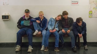 Fünf Jungs sitzen auf einer Bank.