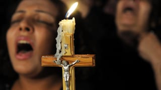 Singende koptische Christen halten ein Kreuz in der Hand.